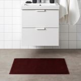 Red rectangular SÖDERSJÖN bath mat with white cabinet and sink.