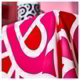 Bright pink and white patterned tablecloth with bold, abstract designs, draped neatly, showcasing high-quality cotton material.