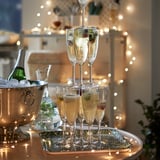 Champagne tower with glasses, bottle in ice-filled SOLDRÄNKT bowl, lights.