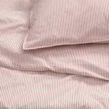Close-up of neatly folded red and white striped bed sheets, showcasing their texture and stitching.