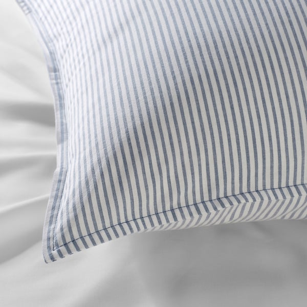 Blue and white striped pillow on white bedding. Close-up detailed stitching and soft fabric texture.