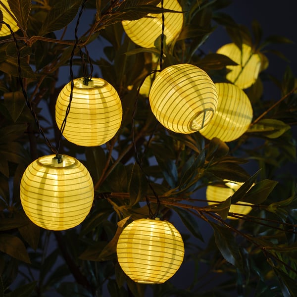 Yellow lanterns among green leaves, casting warm, soft light.