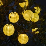 Yellow lanterns among green leaves, casting warm, soft light.