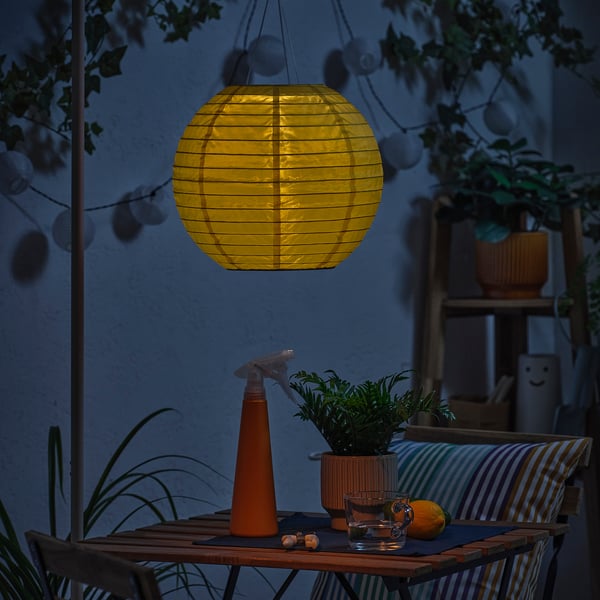 Night patio with solar lantern, watering can, plant, glass, orange.