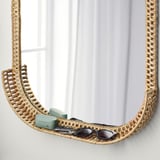 Wicker mirror shelf holds items, natural rattan.