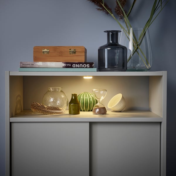Modern cabinet with open shelving showing decorative vases and items, sliding doors for space-saving storage.