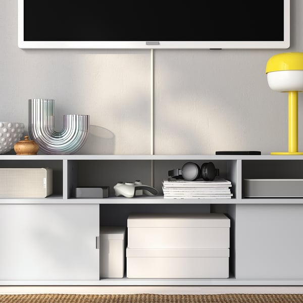 Modern tv stand with shelves holding books, boxes, and decorations, supporting a flat-screen tv above.