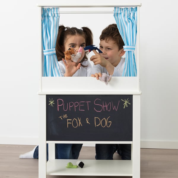 Kids perform puppet show with puppets in white theater.
