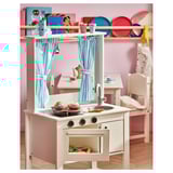 Childs white play kitchen with striped curtains, stove, sink, and toy food. Bright pink and blue accessories.