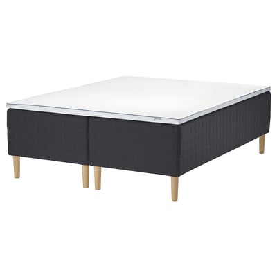 A black and white STAVANGER bed with wooden legs, featuring pocket springs and memory foam for comfort.