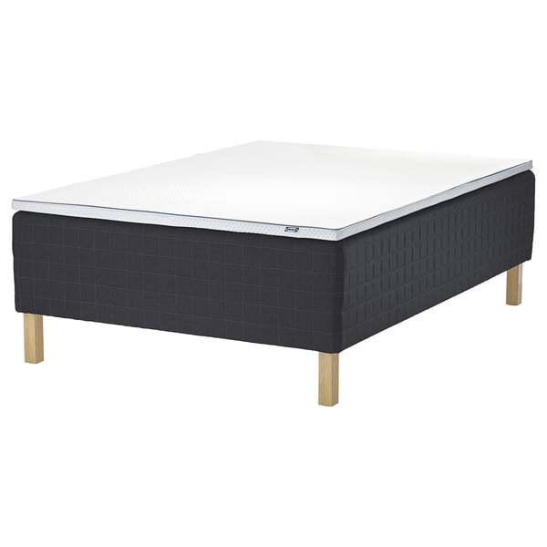 STAVANGER mattress base in black, made of wood with light wood legs, featuring a white mattress.