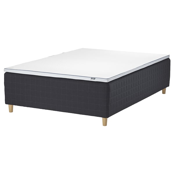 A STAVANGER bed in black with a white mattress. The bed has wooden legs and a padded base.