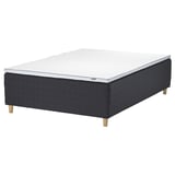 A STAVANGER bed in black with a white mattress. The bed has wooden legs and a padded base.
