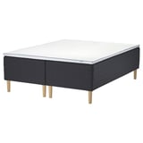 Image depicts a black and white STAVANGER mattress on a wooden base with light wooden legs.