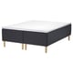 Image depicts a black and white STAVANGER mattress on a wooden base with light wooden legs.