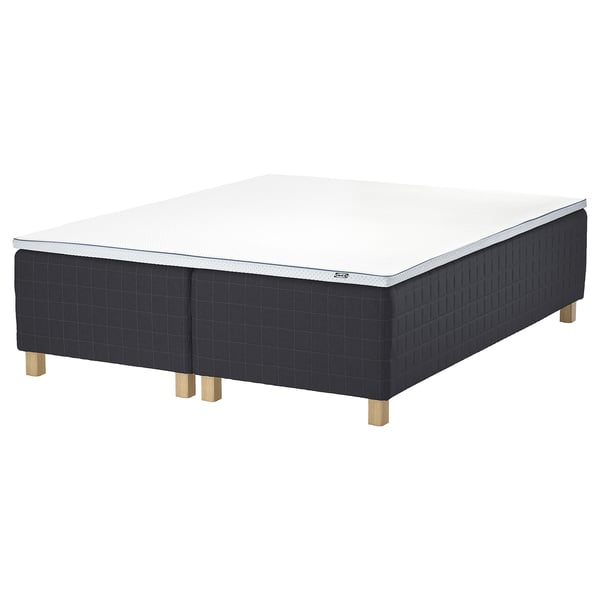 A black STAVANGER bed base with a white mattress; it has wooden legs and a quilted design.