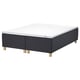A black STAVANGER bed base with a white mattress; it has wooden legs and a quilted design.