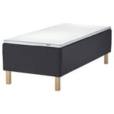 Black ikea STAVANGER bed with dark grey quilted frame and light wooden legs. Mattress has white and grey textured surface for comfort and support.
