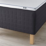 Close-up of ikea mattress on dark base with wooden legs.