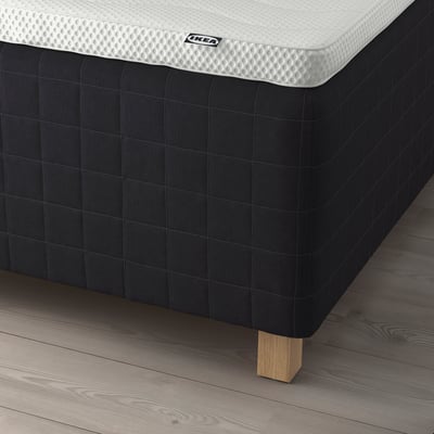 Image a mattress over black bed base. Legs visible, indicating its raised.