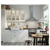 Modern kitchen with white cabinets, black countertops, stainless steel appliances, and a black chair near a wooden table.