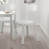 Two white STEIN stackable chairs near a small table. Lightweight, durable plastic, ideal for compact dining.