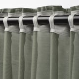 Green STENFRÖ sheer curtains hang with white heading tape, creating elegant pleats. Daylight softens, offering privacy.