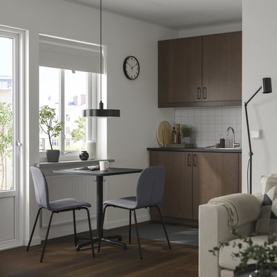 Modern kitchen with black STENSELE table and grey chairs, near wooden kitchenette.