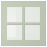 A light green, square-shaped, four-paneled window with a wooden frame.