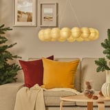 Cozy living room with beige sofa, colorful pillows, hanging gold lanterns, and decorated christmas tree.