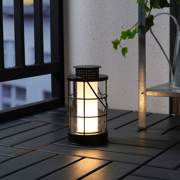 Cozy black outdoor lantern on a table, lit with warm led light, perfect for any evening ambience.