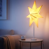 Cozy indoor lamp on table with star-shaped shade, providing warm light.