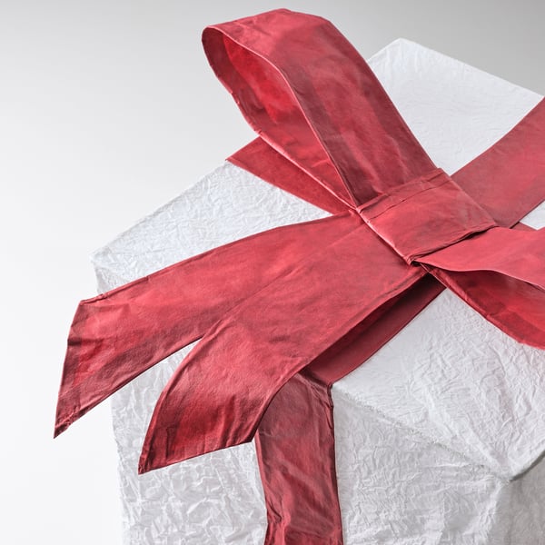 White gift box with shiny, large red bow tied around it.
