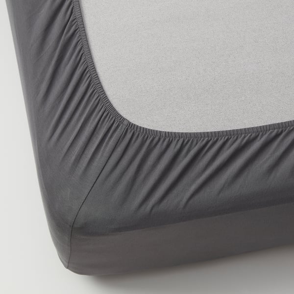 Close-up of grey fitted sheet with elastic edges, tightly covering a foam mat, highlighting its snug fit and quality.