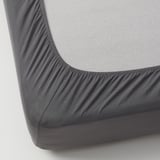 Close-up of grey fitted sheet with elastic edges, tightly covering a foam mat, highlighting its snug fit and quality.