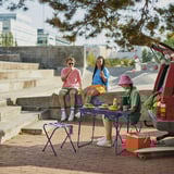 Friends dining outside with drinks and skateboard. 81 characters