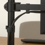 Black adjustable monitor arm with cables managed by clips, attached to a wooden desk.