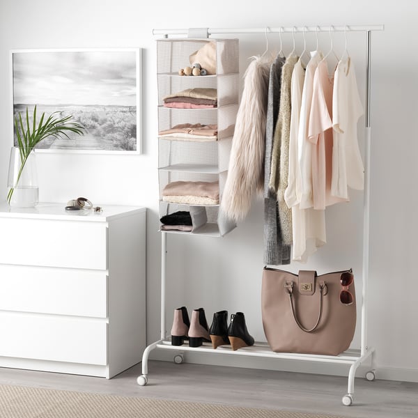 Clothes rack with hanging garments and storage shelves with folded items.
