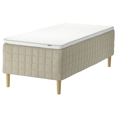 Depicts an IKEA STUVLAND white and beige mattress with wooden legs, featuring a pocket spring design.