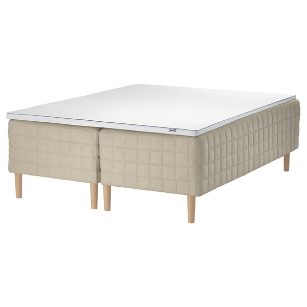 A beige and white STUVLAND bed with wooden legs. It a textured linen side and a bonnell spring base.