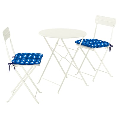 A white outdoor table with two matching foldable chairs and blue cushions. Modern, compact design, ideal for balconies.