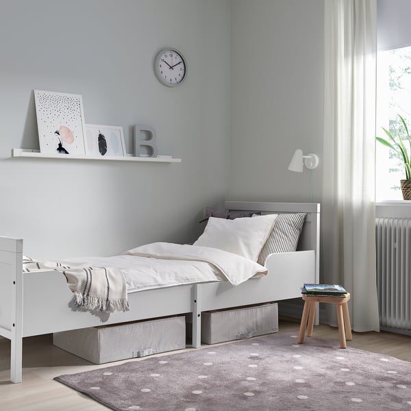 Minimalist kids room with white SUNDVIK bed, art shelf, lamp & rug.