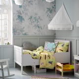 Kids room with white SUNDVIK bed, yellow bedding, floral wallpaper, and gray walls.