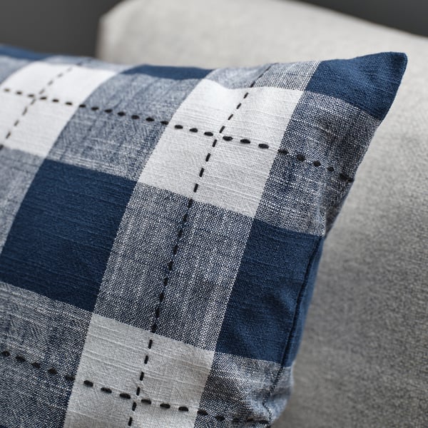 Close-up of a striped cushion cover with dark blue and white pattern, showing intricate stitching.