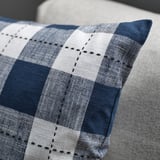 Close-up of a striped cushion cover with dark blue and white pattern, showing intricate stitching.