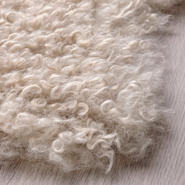 Soft, curly white rug on wooden floor; cozy, textured