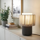 SYMFONISK black speaker lamp on cabinet with books & plant.