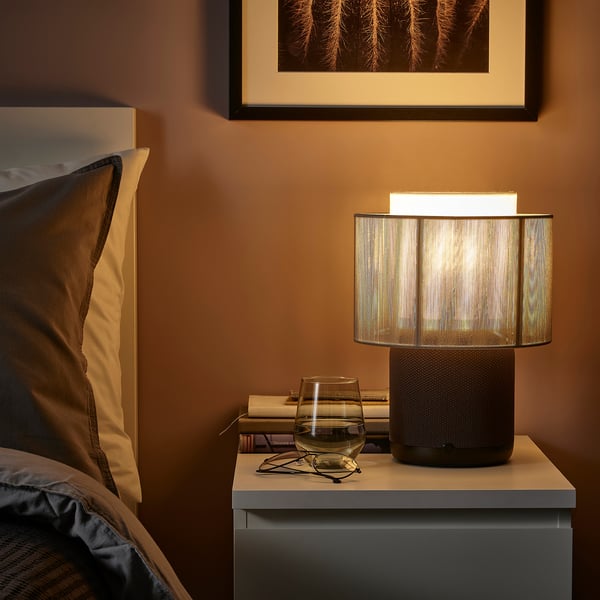 SYMFONISK lamp & speaker combo on bedside table with wine glass and books.