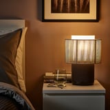 SYMFONISK lamp & speaker combo on bedside table with wine glass and books.