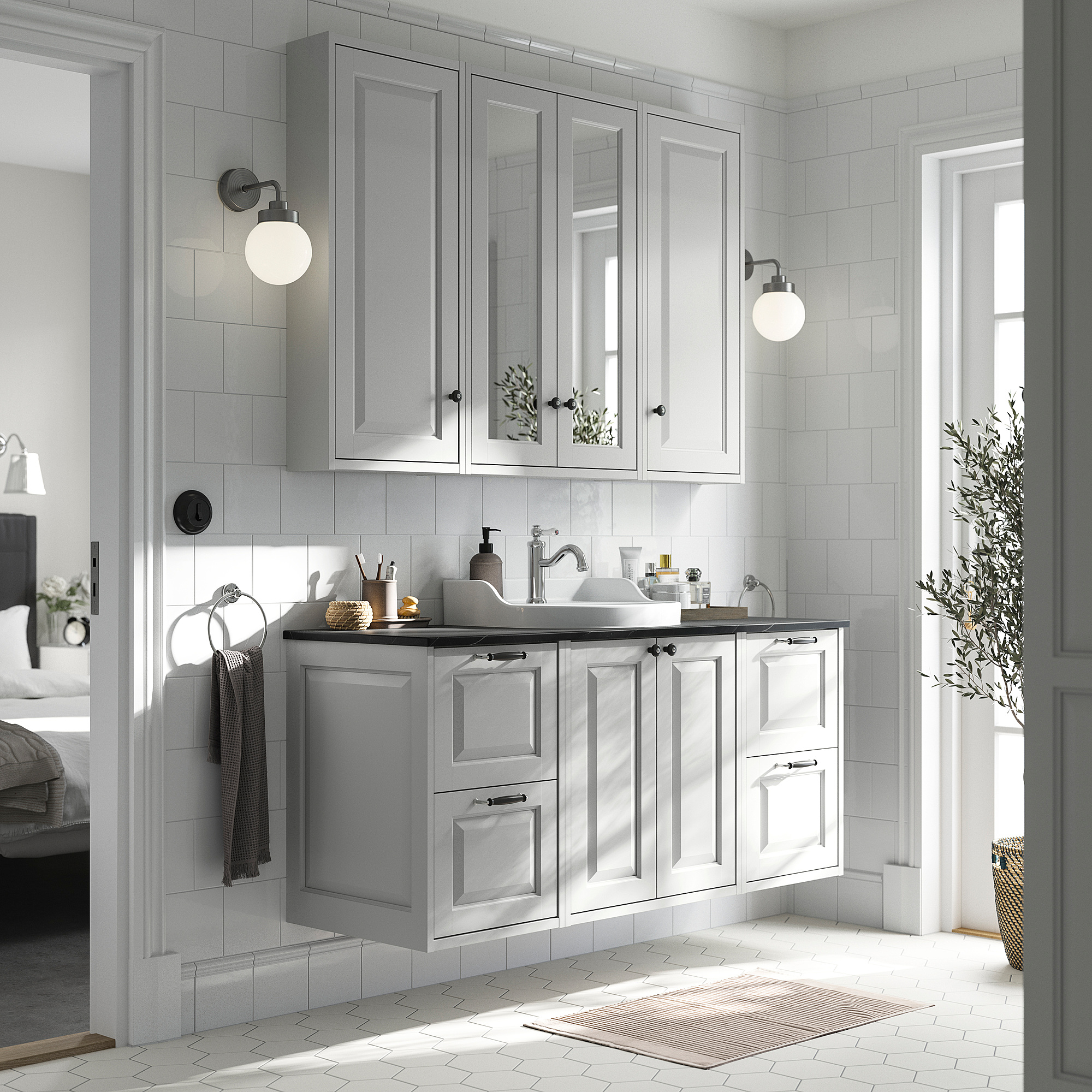 Modern bathroom with light grey TÄNNFORSEN cabinet set, marble counter, wall lamps, and plant.
